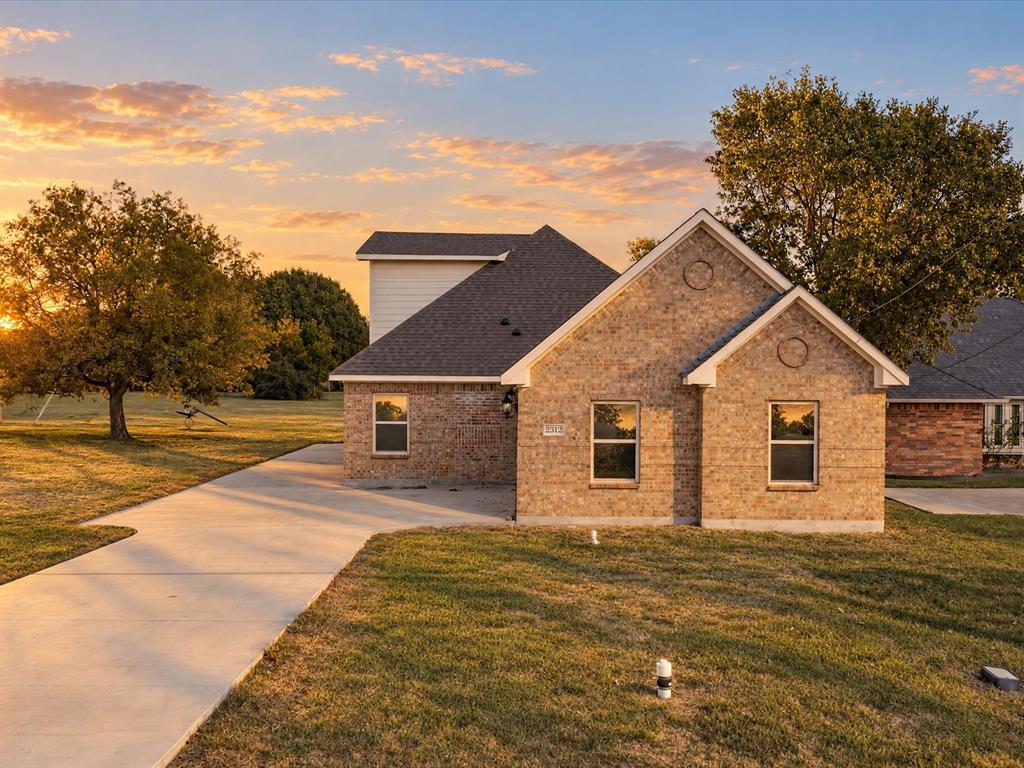 Brick exterior featuring a gabled roofline, concrete driveway, and rectangular windows