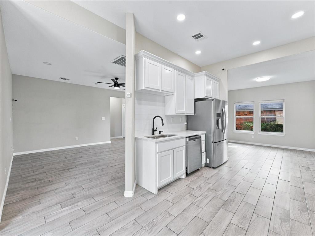 Kitchen featuring white cabinetry, wood-finish flooring, stainless steel appliances, and a matte black faucet