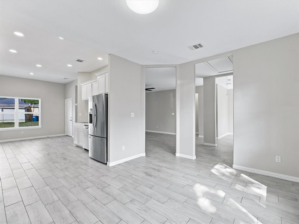 Neutral interior featuring wood-finish tile flooring, recessed lighting, white cabinetry, and stainless steel appliances