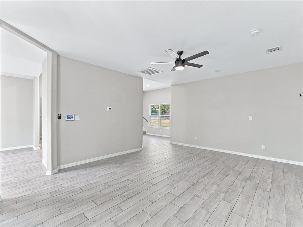 Interior space featuring wood-finish tile flooring, neutral wall paint, a multi-blade ceiling fan with integrated lighting, and recessed ceiling illumination