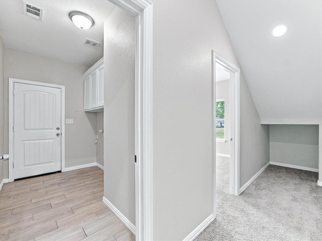 Hallway featuring wood-finish flooring, white upper cabinetry, ceiling-mounted lighting, and carpeted flooring