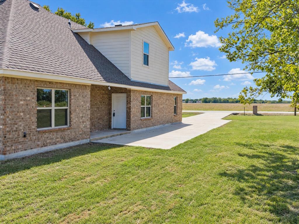 Brick and siding exterior featuring a concrete walkway, multi-gable roofline, and expansive surrounding grounds
