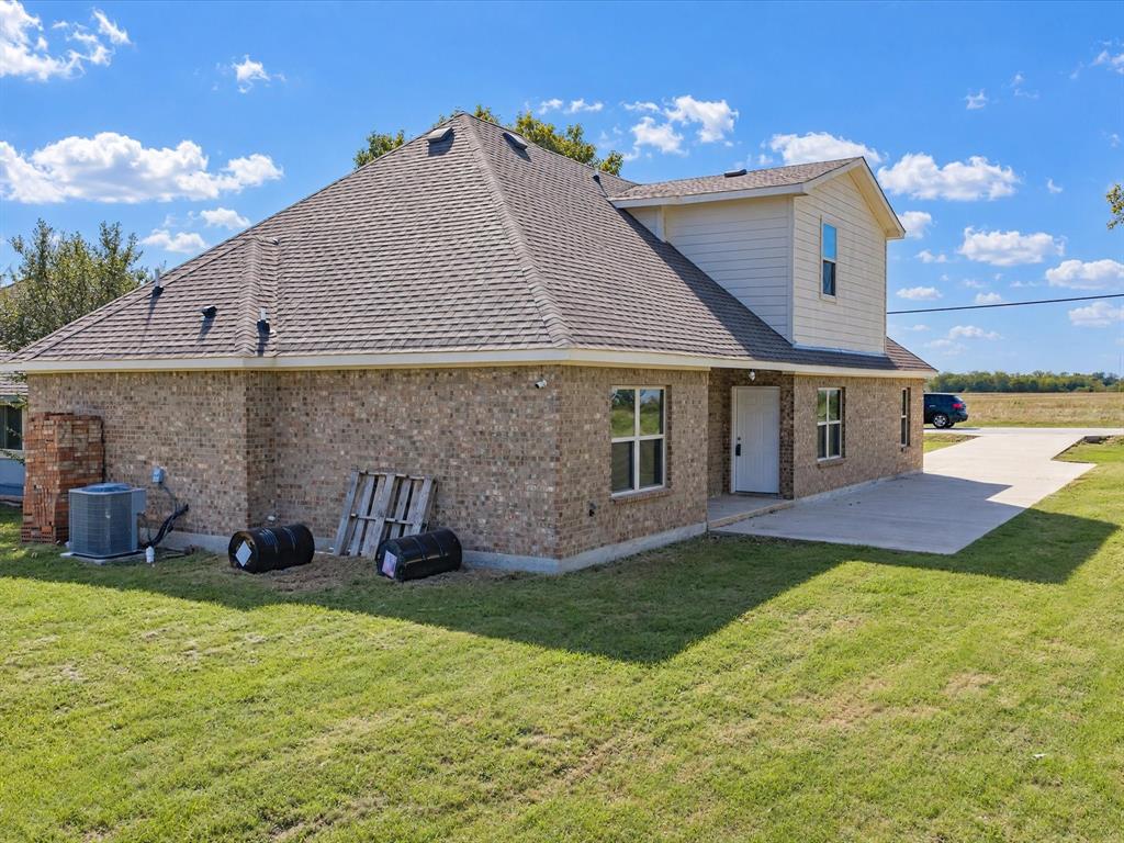 Multi-level exterior featuring a brick and composite siding facade, a composition shingle roof, a concrete driveway, and a concrete patio