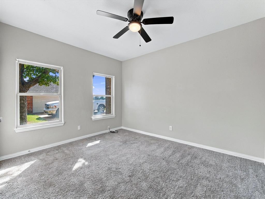 Neutral-toned interior space featuring wall-to-wall carpeting, dual windows, and an integrated ceiling fan with a centered light fixture