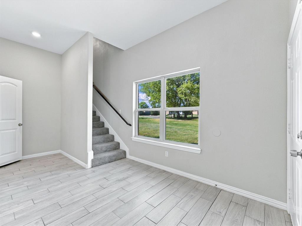 Interior space featuring wood-finish tile flooring, recessed lighting, carpeted staircase with a dark handrail, and large-format windows