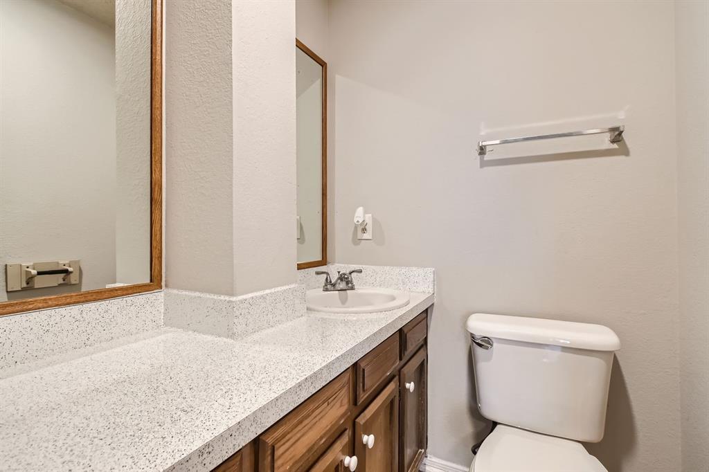 Bathroom vanity featuring a speckled composite countertop, undermount sink with dual-handle faucet, wood cabinetry, and framed wall mirror