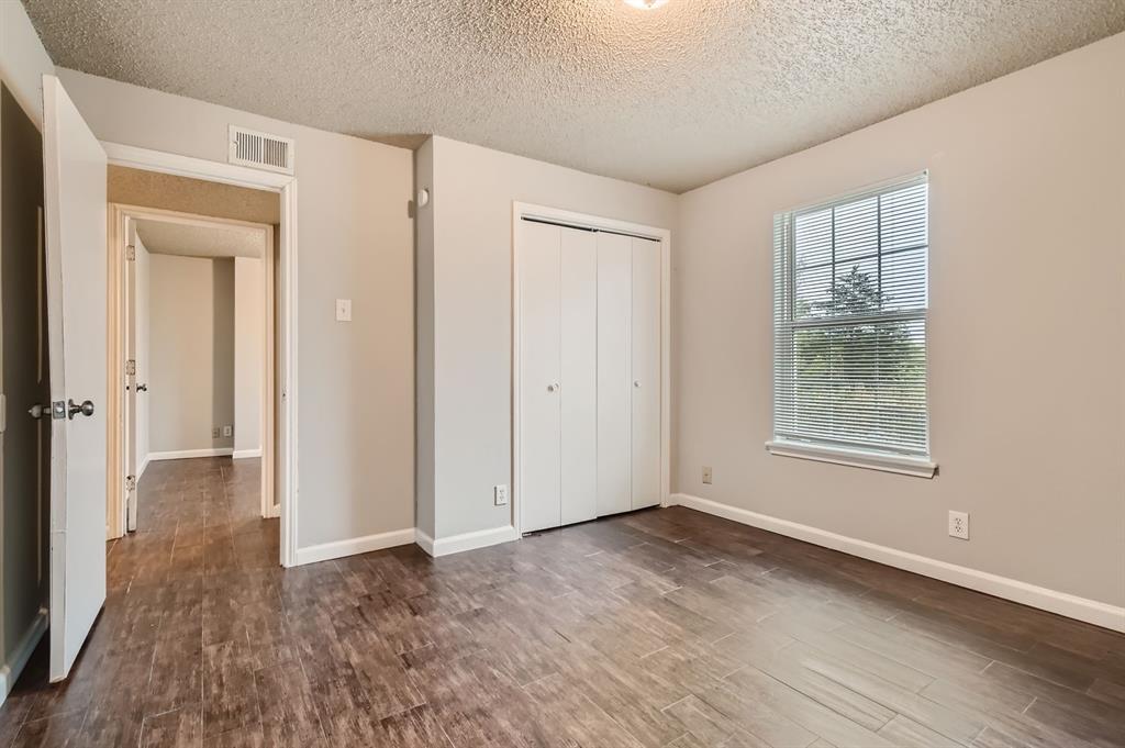 Wood-finish flooring, neutral wall tones, single-hung window with horizontal blinds, and a dual-panel closet door