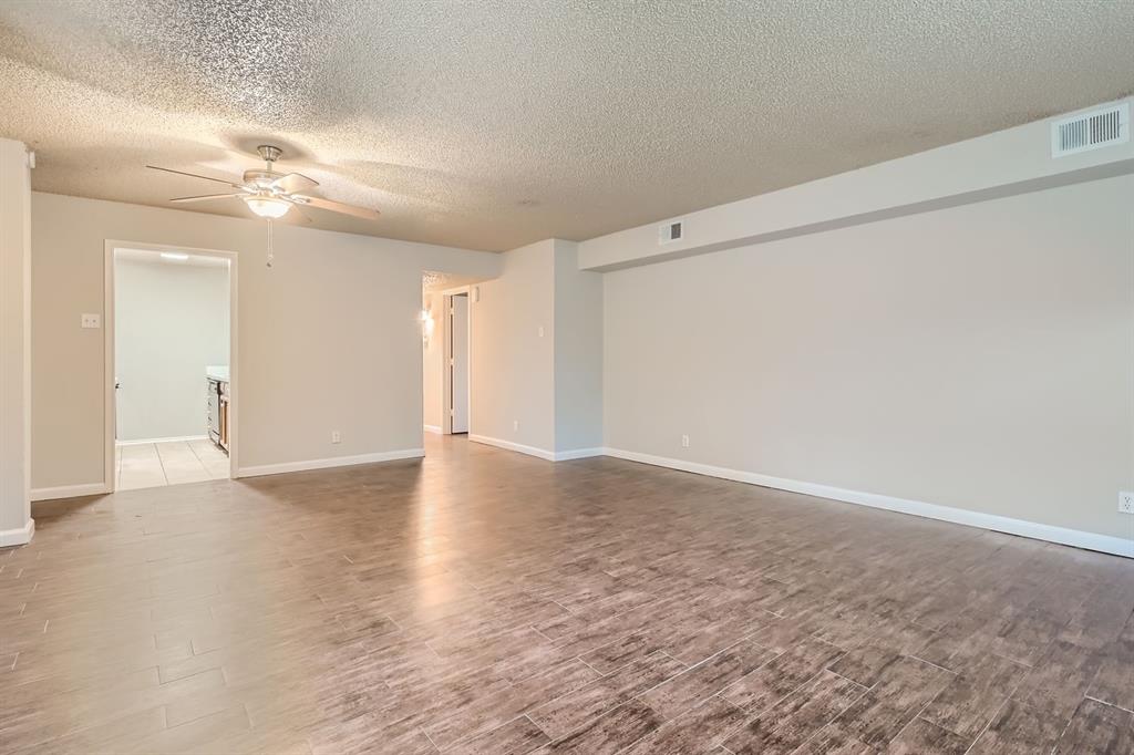 Open-concept room featuring wood-finish flooring, a ceiling fan with integrated lighting, and neutral wall paint