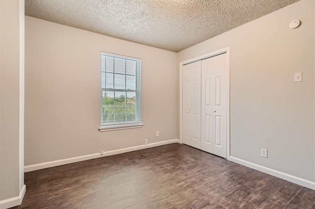 Room featuring wood-finish flooring, a single-pane window, and a built-in closet with double doors