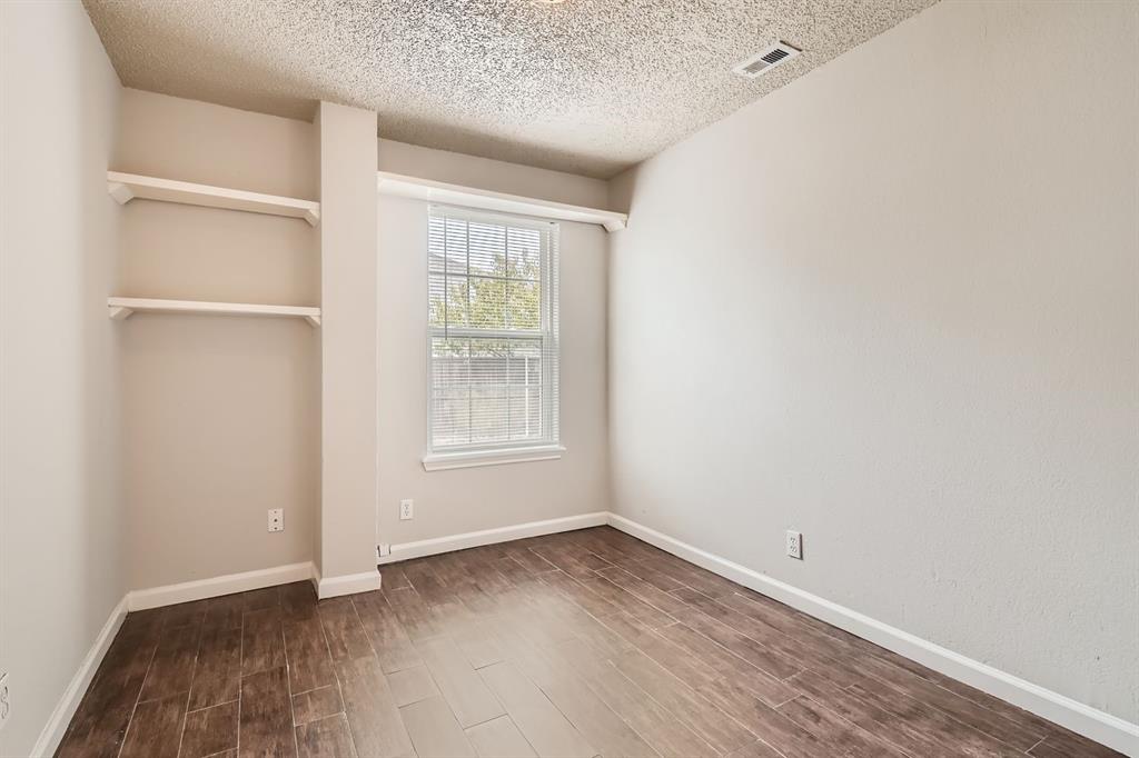 Room featuring wood-finish flooring, built-in shelving, neutral wall paint, and a single-pane window
