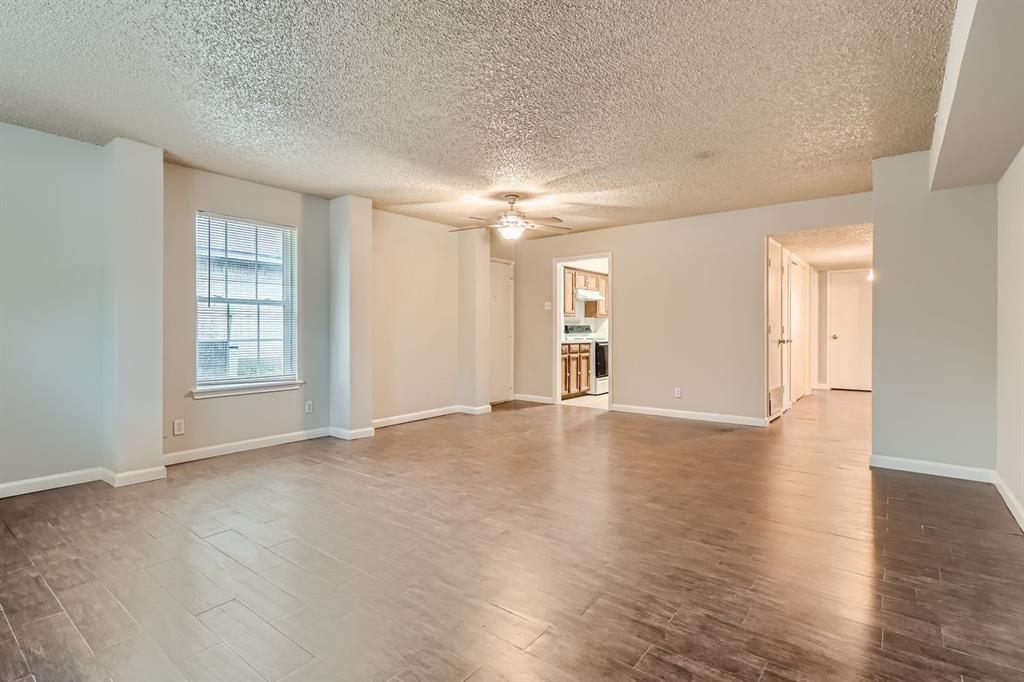 Open-concept room featuring wood-finish flooring, a ceiling fan with integrated lighting, and neutral wall tones