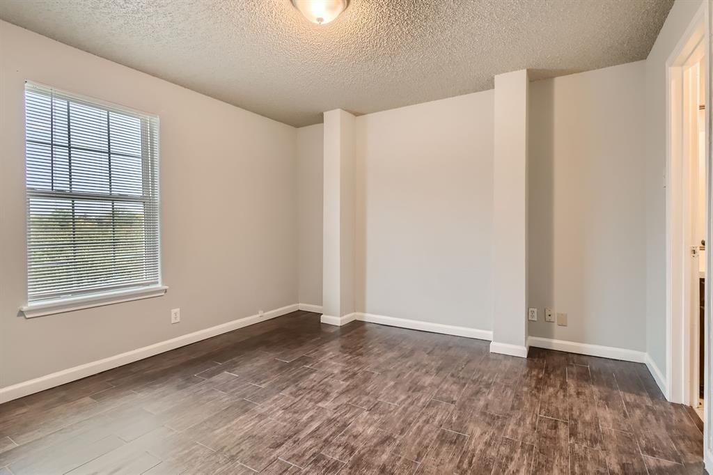 Room featuring wood-finish tile flooring, textured ceiling, flush-mount lighting, and a multi-pane window