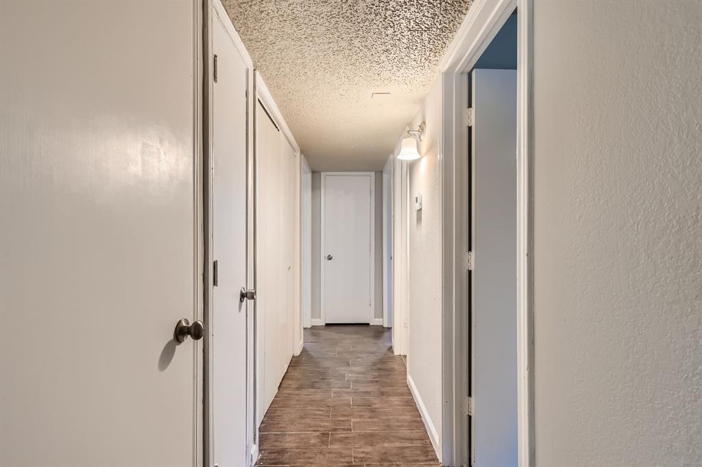Hallway featuring tile flooring, multiple interior doors, and a wall-mounted light fixture