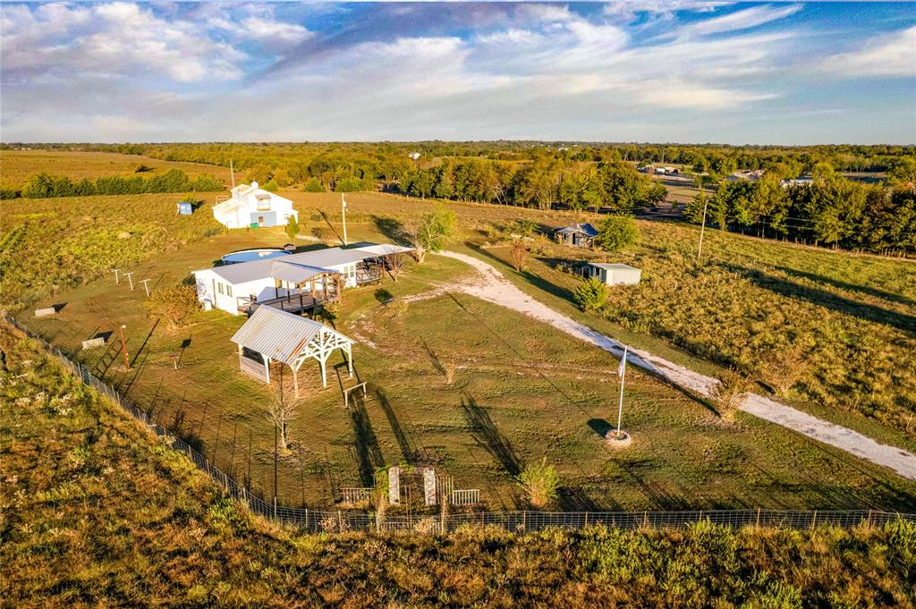 Expansive acreage featuring a gated perimeter, gravel driveway, detached metal pavilion, and multiple outbuildings