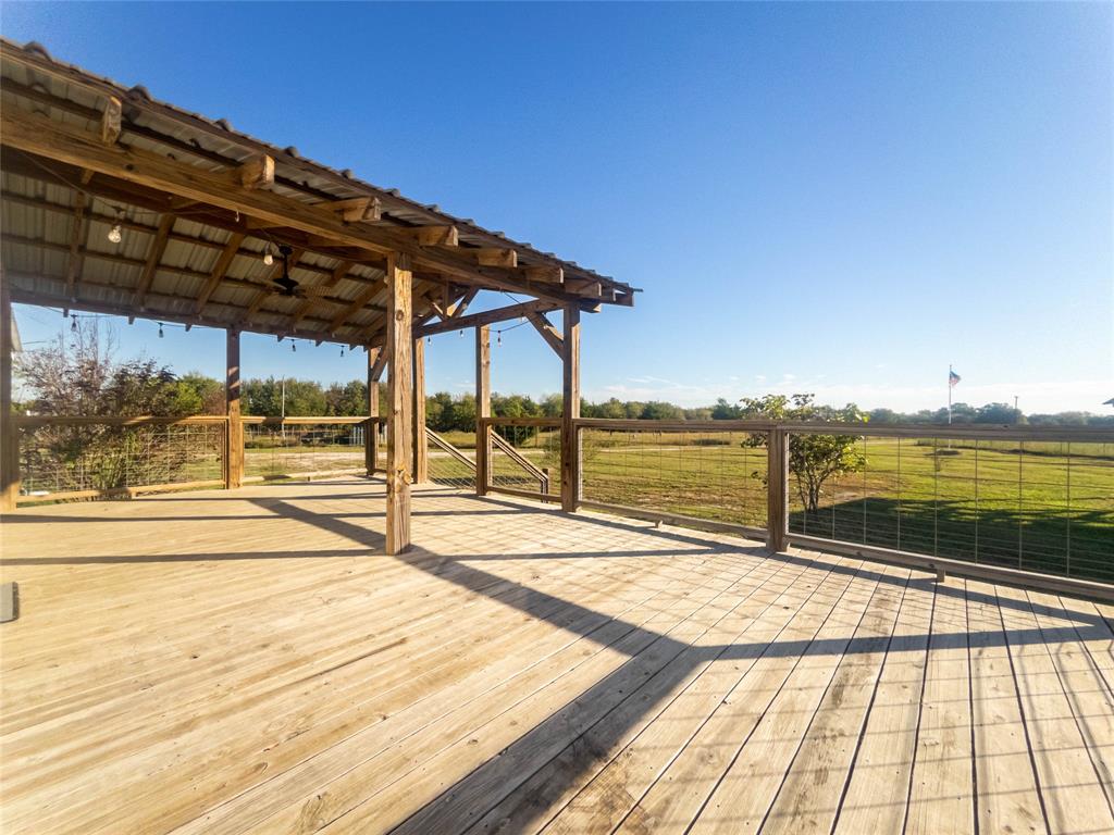 Expansive wood deck featuring a covered timber-framed pavilion, metal roof, and wire mesh perimeter railing