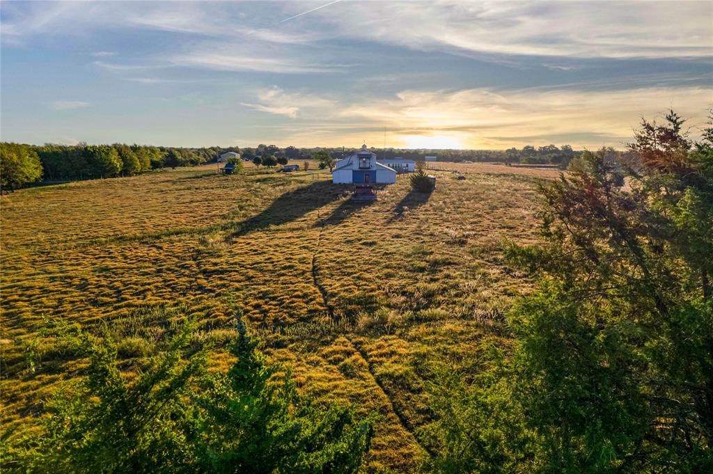Expansive acreage featuring open pasture land, mature perimeter trees, and a detached outbuilding