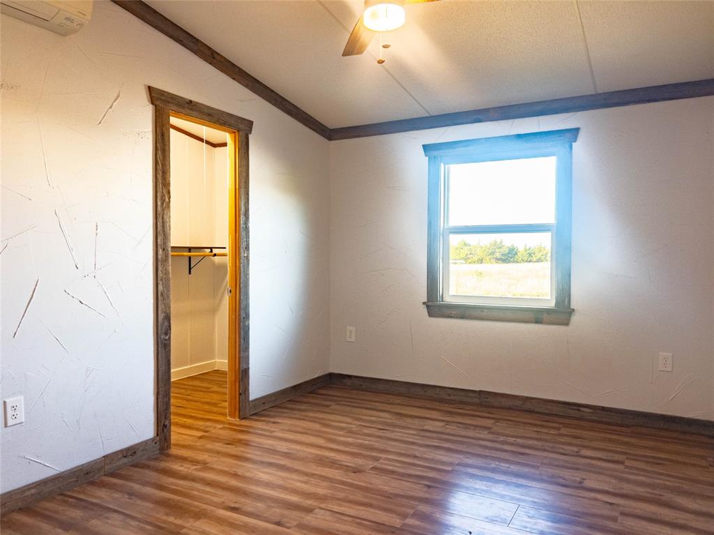 Textured wall finishes, wood-finish flooring, wood-trim door and window casing, ceiling fan, and built-in closet shelving