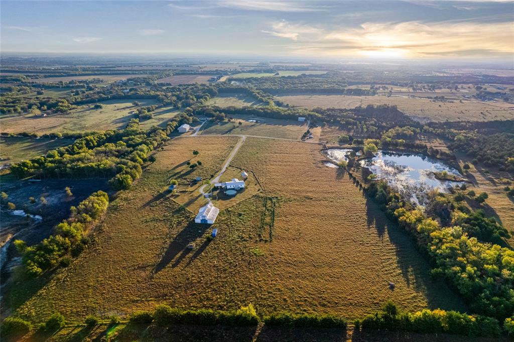Expansive acreage featuring cleared pasture land, multiple outbuildings, a private pond, and mature tree lines