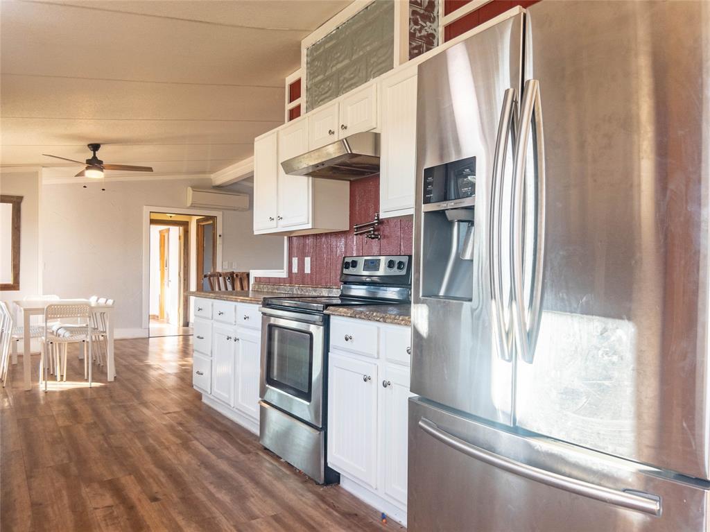 Kitchen featuring white cabinetry, stainless steel appliances, wood-finish flooring, and a ceiling fan