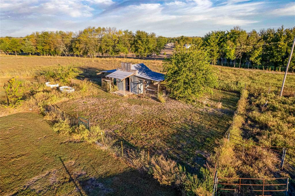Rural property featuring a structure with a metal roof, expansive open acreage, and perimeter fencing