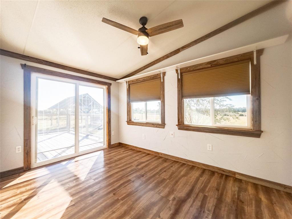Wood-finish flooring, sliding glass door, dual pane windows with integrated window shades, wood-trim accents, and a ceiling fan with light fixture
