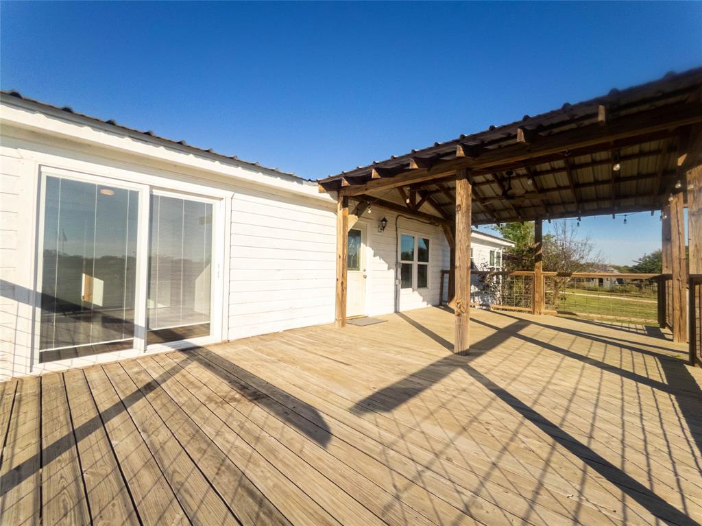 Expansive wood-plank deck featuring a covered timber-framed patio, metal roofing, and cable-rail fencing