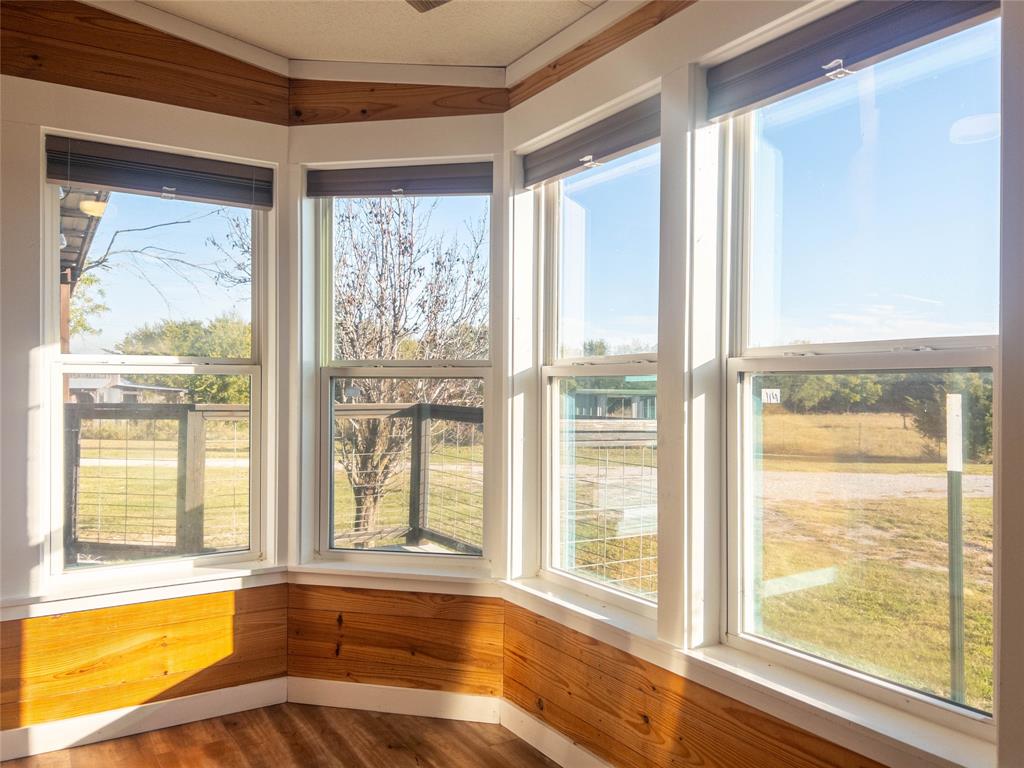 Bay window featuring multi-pane glass, natural wood-finish wainscoting, white trim, and retractable shades