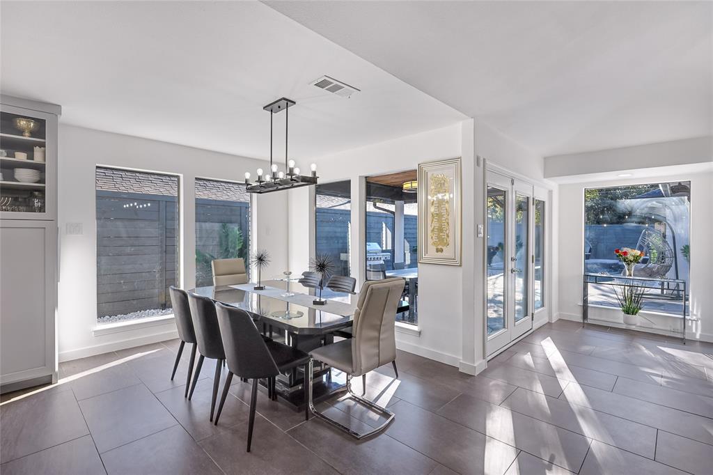 Large-format tile flooring, built-in cabinetry, linear multi-light fixture, expansive window groupings, and glass-paned double doors