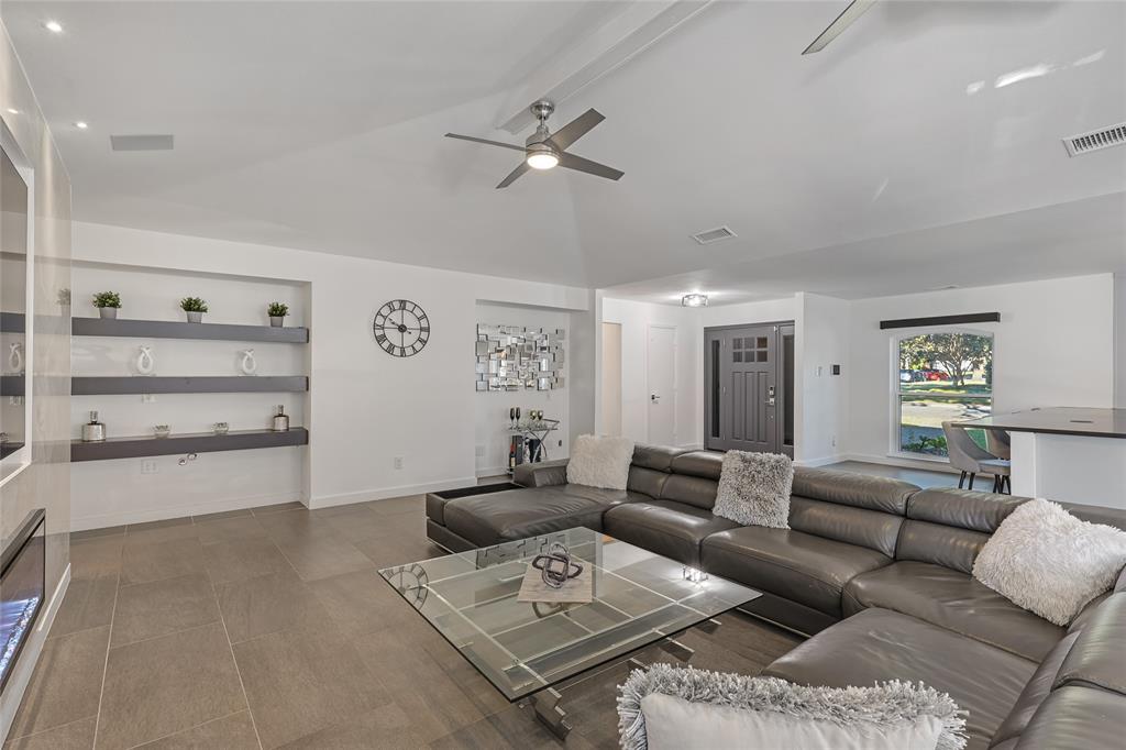 Vaulted ceilings featuring recessed lighting, built-in recessed shelving, large-format tile flooring, and a linear electric fireplace