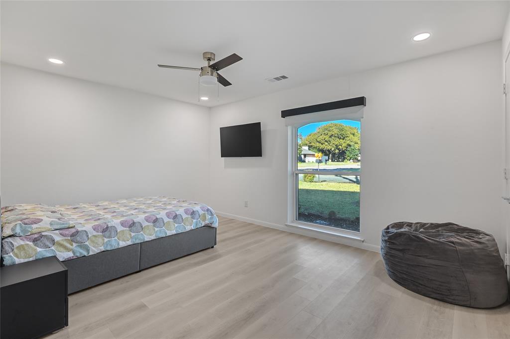 Light-filled room featuring wood-finish flooring, recessed lighting, a modern ceiling fan, and an arched window