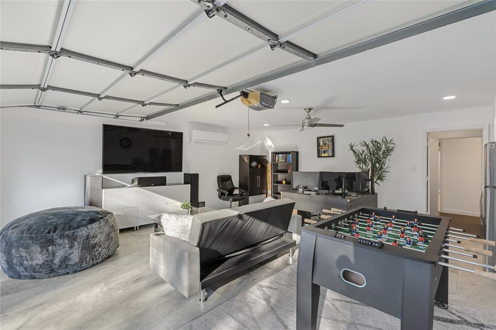 Finished garage space featuring wood-finish flooring, recessed lighting, a ceiling fan, and a wall-mounted ductless heating and cooling unit