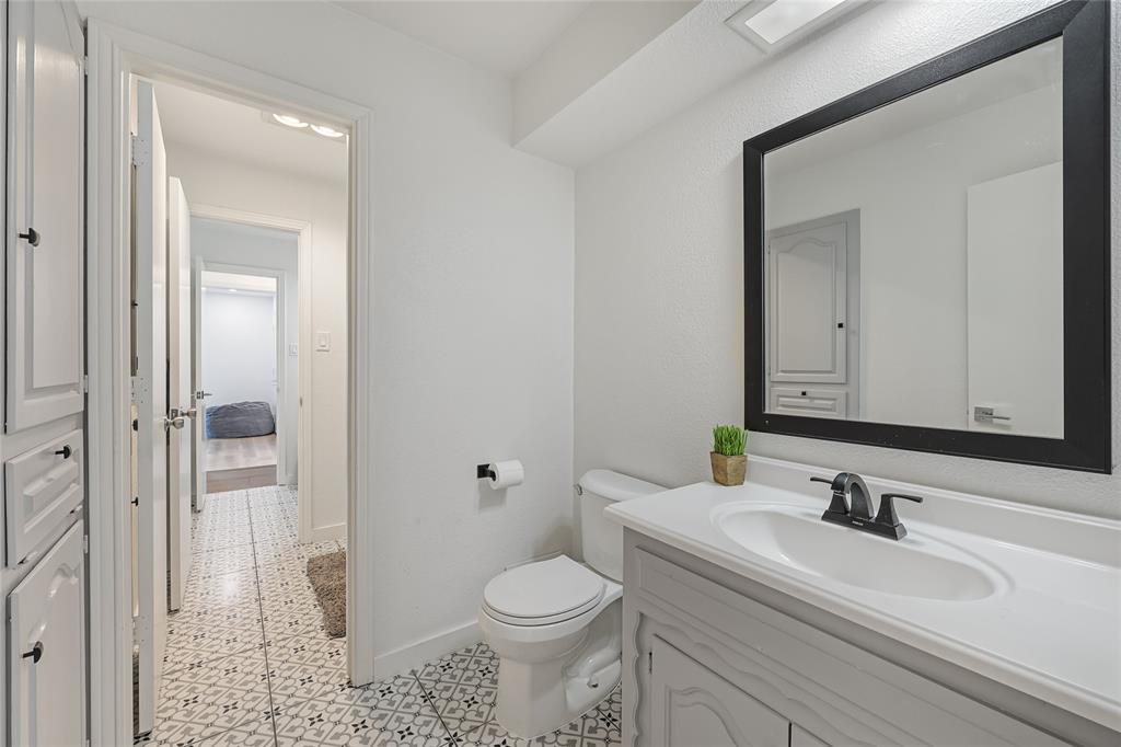 Bathroom featuring a gray vanity with an integrated basin, matte black faucet, framed mirror, and patterned tile flooring