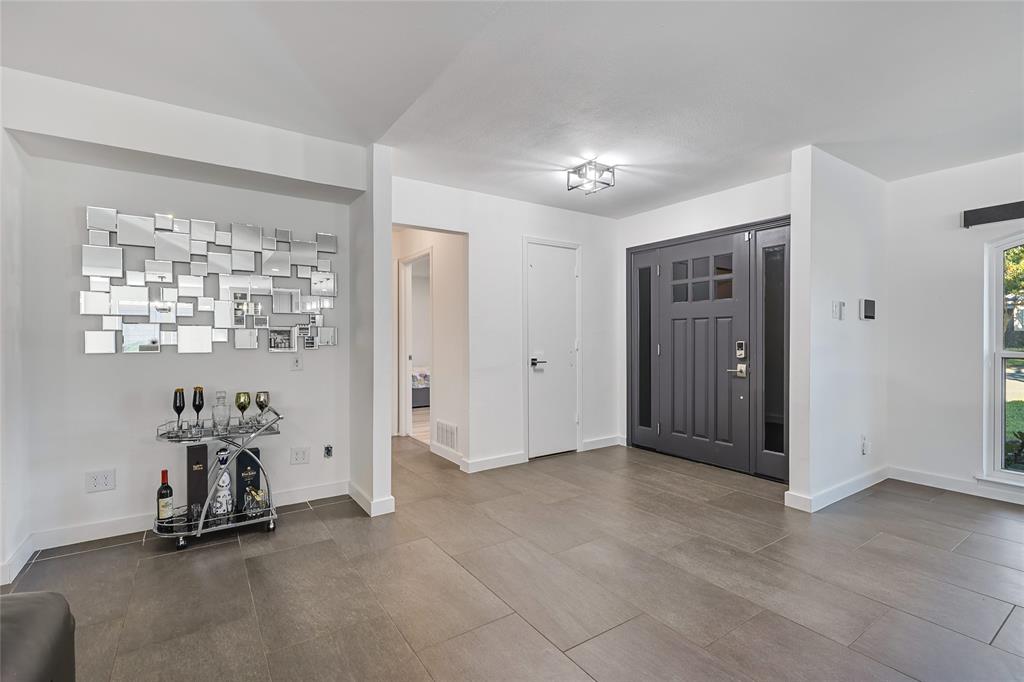 Entryway featuring large-format tile flooring, a charcoal-toned front door with glass panel detailing, and a multi-light flush mount ceiling fixture