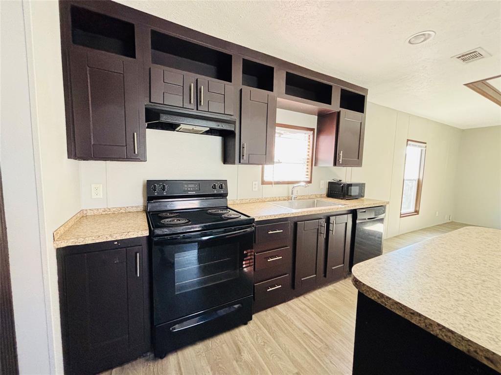Kitchen featuring dark cabinetry with crown molding, stone-patterned countertops, recessed lighting, and wood-finish flooring