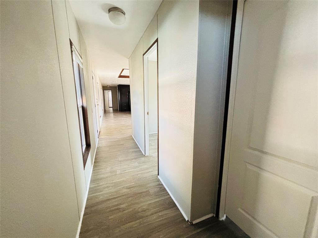 Hallway featuring wood-finish flooring, neutral wall tones, ceiling-mounted lighting, and paneled interior doors