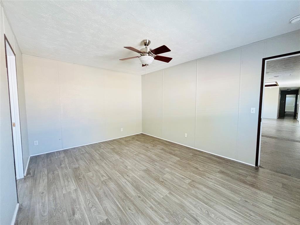Room featuring light-toned paneling, wood-finish flooring, and a ceiling-mounted light fixture with a fan