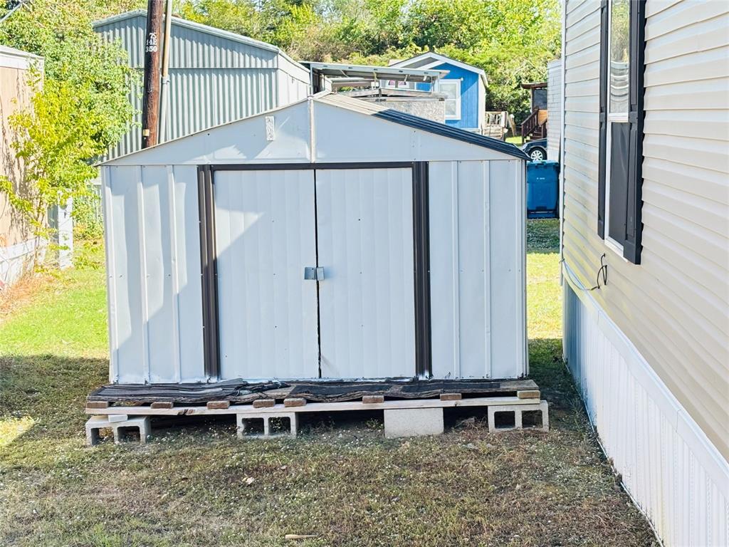 Metal storage shed featuring double-door entry and a foundation constructed of concrete blocks and wood platform