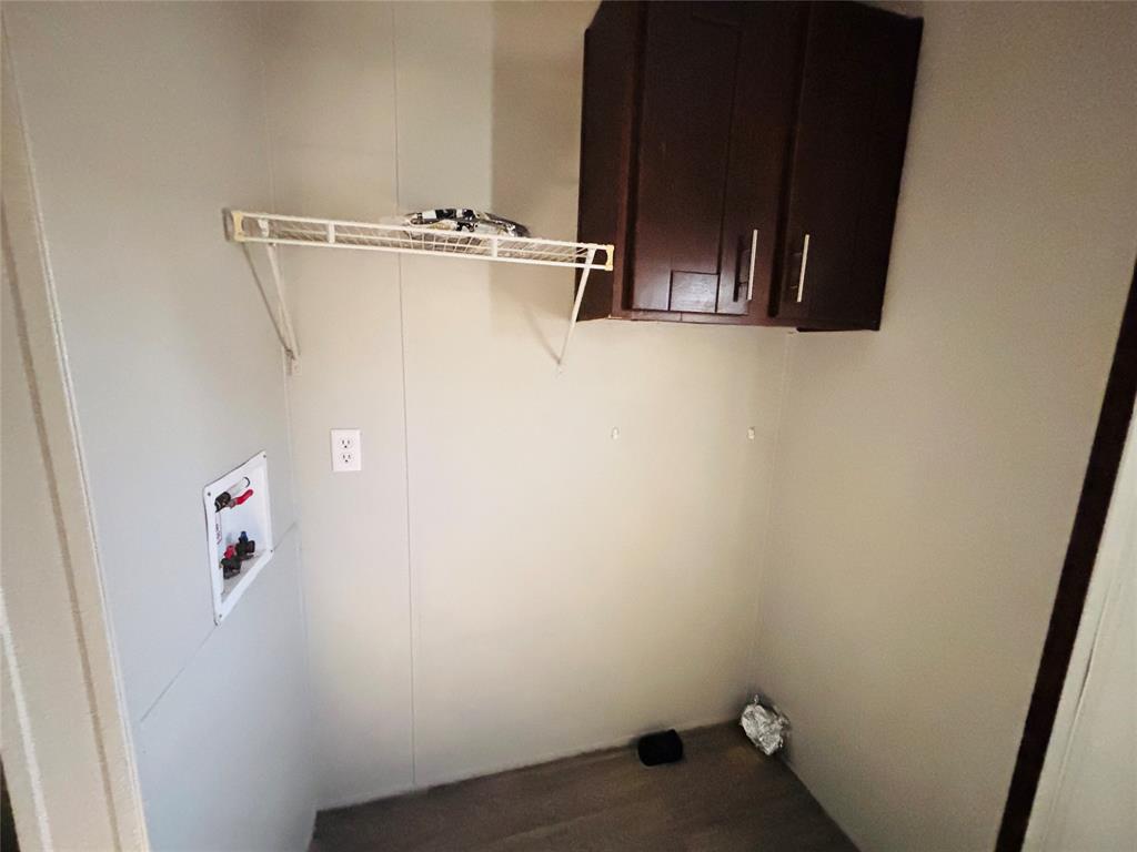Utility space featuring dark-finish upper cabinetry, wire shelving, and dedicated plumbing connections