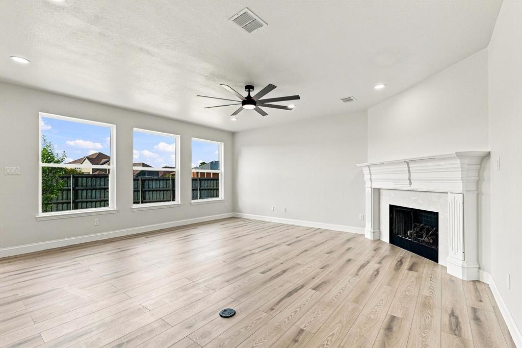 Living area featuring wood-finish flooring, a white decorative fireplace mantel, three large windows, recessed lighting, and a multi-blade ceiling fan