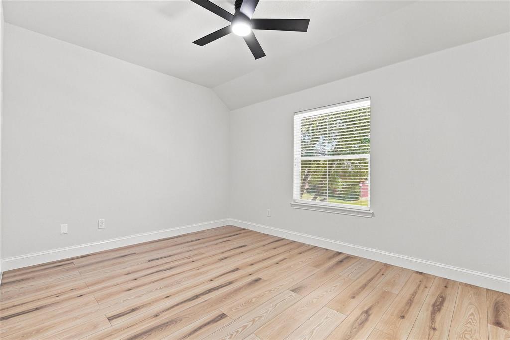 Room featuring wood-finish flooring, vaulted ceiling, and a matte black ceiling fan with an integrated light fixture