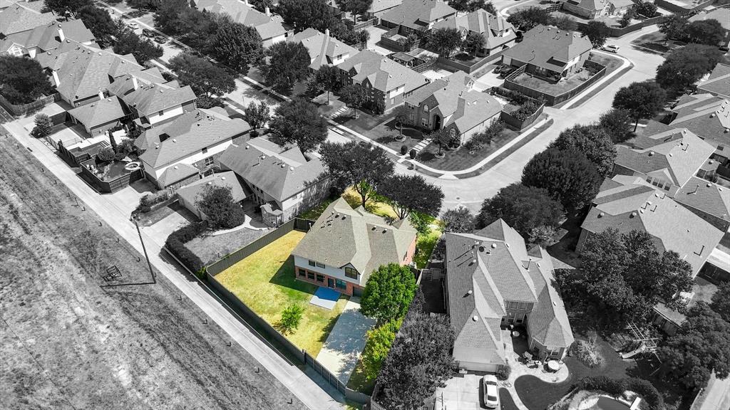 Aerial perspective of a multi-story residence situated on a corner lot featuring a fenced backyard, mature trees, and concrete driveway