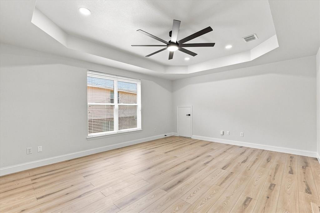 Tray ceiling featuring recessed lighting, multi-blade ceiling fan, and wood-finish flooring