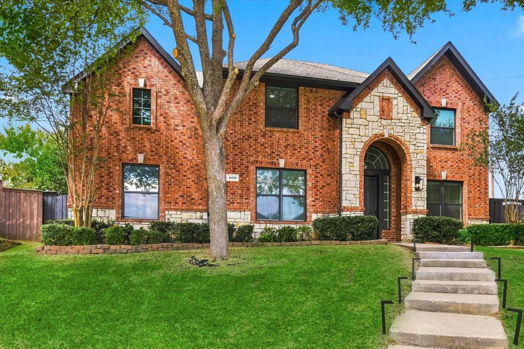 Two-story brick exterior featuring a stone-accented facade, an arched entryway, shingle roofing, and concrete front steps