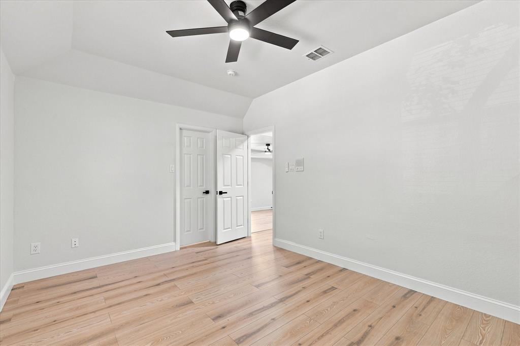 Room featuring wood-finish flooring, tray ceiling, and a matte black ceiling fan with integrated lighting