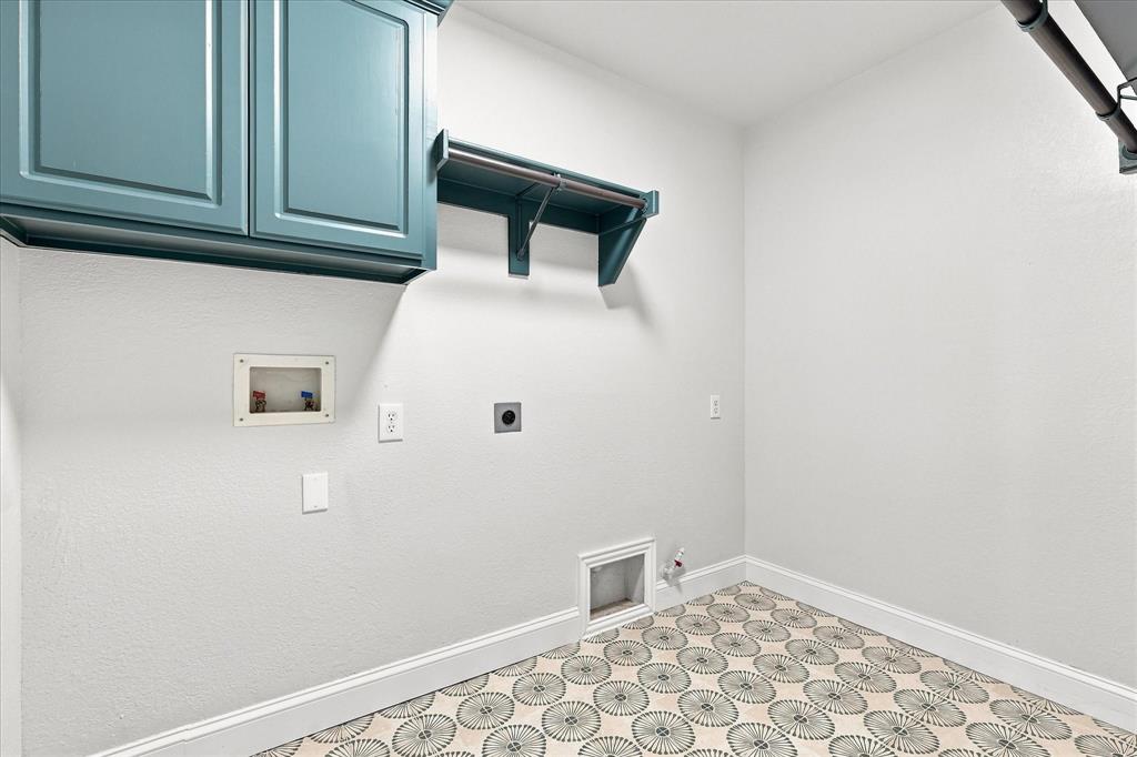 Utility room featuring blue wall-mounted cabinetry, integrated hanging rods, and patterned tile flooring