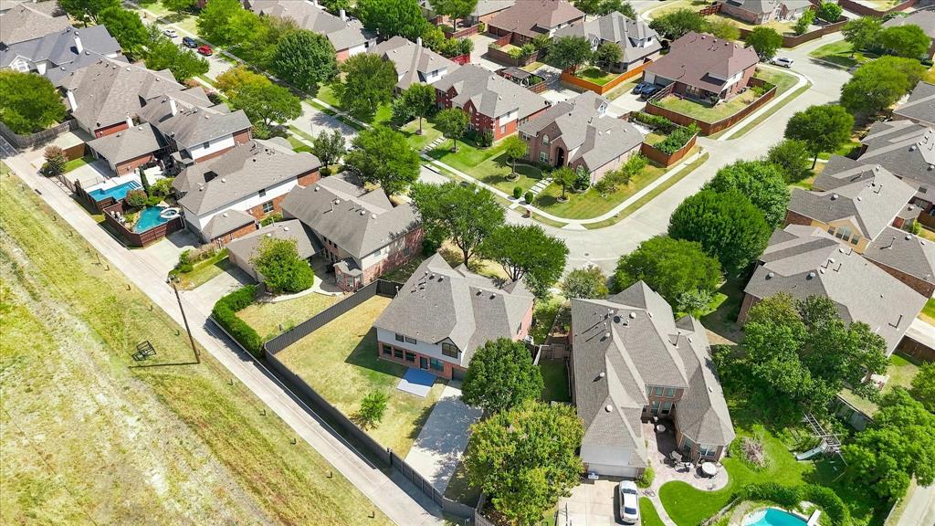 Aerial perspective of a residential neighborhood featuring multi-story dwellings, paved roadways, mature trees, and landscaped grounds