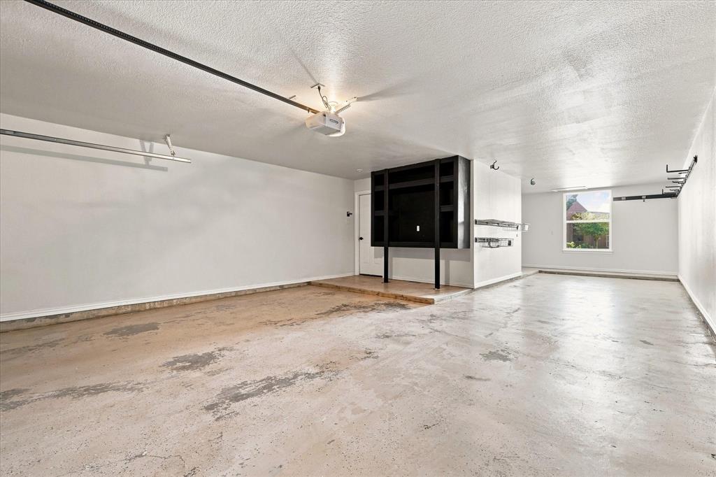 Multi-car garage featuring concrete flooring, built-in black cabinetry, overhead storage racks, and a single-pane window