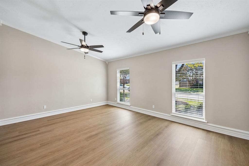 Fresh, neutral tones and attractive wood-look flooring create a bright, versatile living space ready to accommodate a variety of design styles. Crown molding, crisp white baseboards, and ceiling fans add understated elegance and everyday comfort, while generously sized windows invite natural light and offer pleasant views of the surrounding greenery.