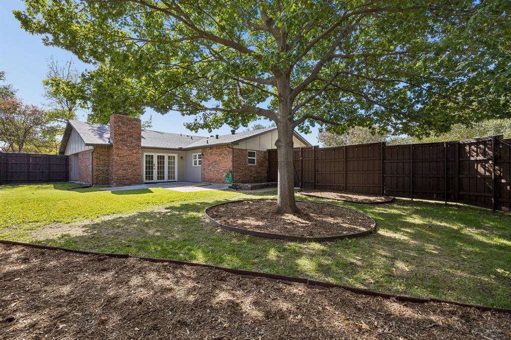 A mature shade tree serves as the centerpiece of this inviting backyard, offering natural beauty and a welcome retreat from the Texas sunshine. The fenced yard provides privacy, while the combination of grassy areas and landscaped mulch beds creates opportunities for outdoor enjoyment, gardening, or additional landscaping enhancements.