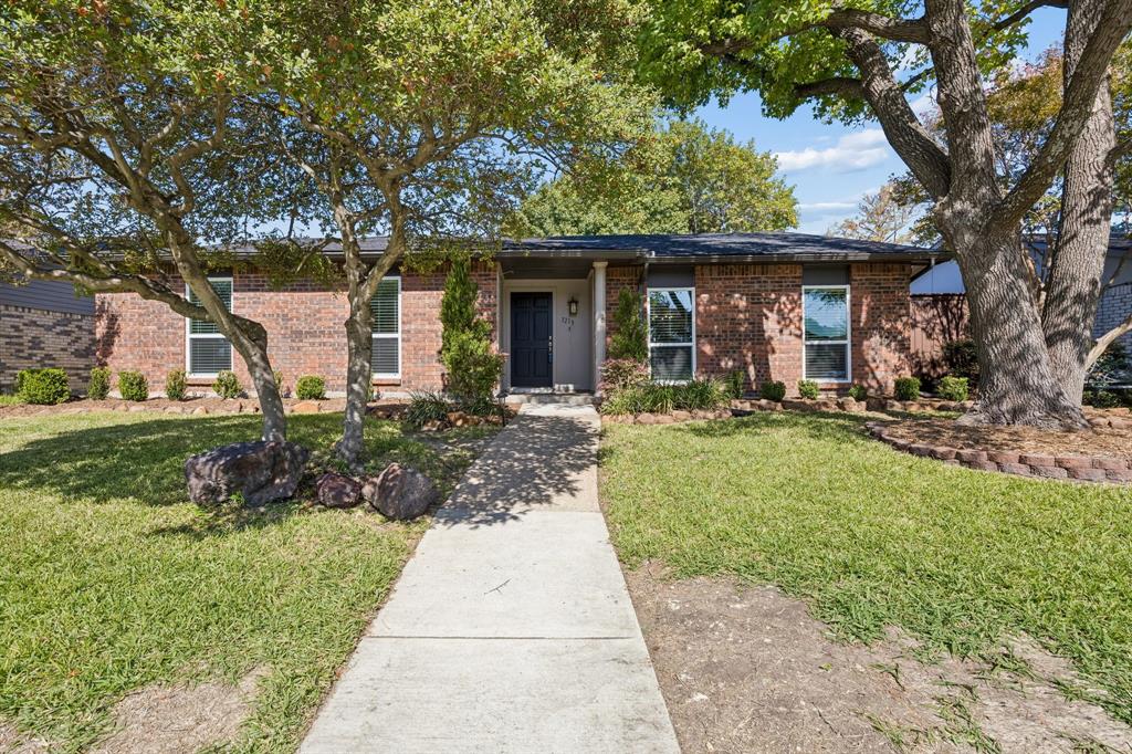 A charming brick exterior welcomes you with timeless appeal, mature shade trees, and beautifully established landscaping. A welcoming walkway leads to the covered front entry, while the manicured lawn, natural stone accents, and classic architectural details create an inviting first impression.